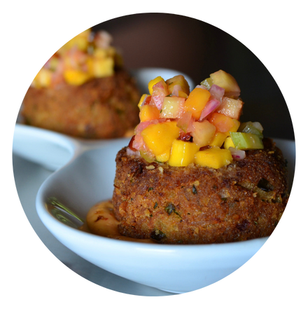 Oblong plate of three crab cakes in an Old Bay aioli topped with mango-fennel salsa