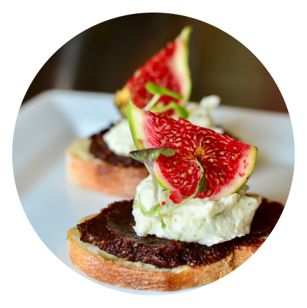 Plate of 2 crostinis topped with fig compote, whipped goat cheese, fresh fig, and microgreens