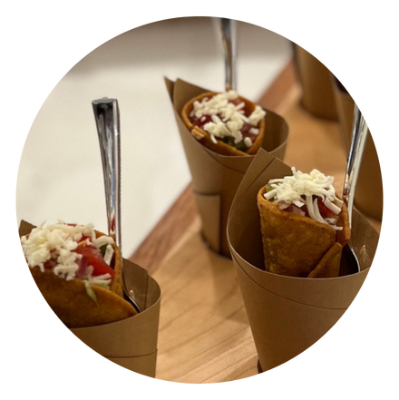 3 handheld fried taco cones in paper with spoons - featuring beef taco meat, cotija cheese, and tomatoes